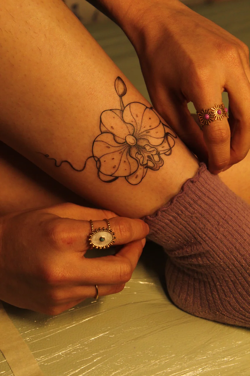 Delicate fine-line floral healed tattoo on forearm